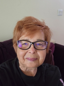 Photo of Marya Liechti, she is wearing a black shirt and has purple glasses and red hair.